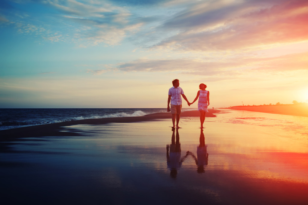 Happy romantic couple walking and holding hands on a beach